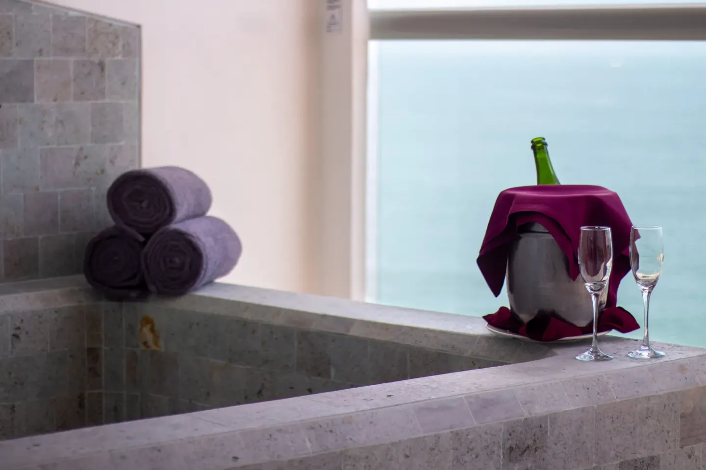 Stone soaking tub with towels and glasses in Deluxe Premium Ocean Front at Sunset Plaza Beach Resort & Spa Pto Vallarta.