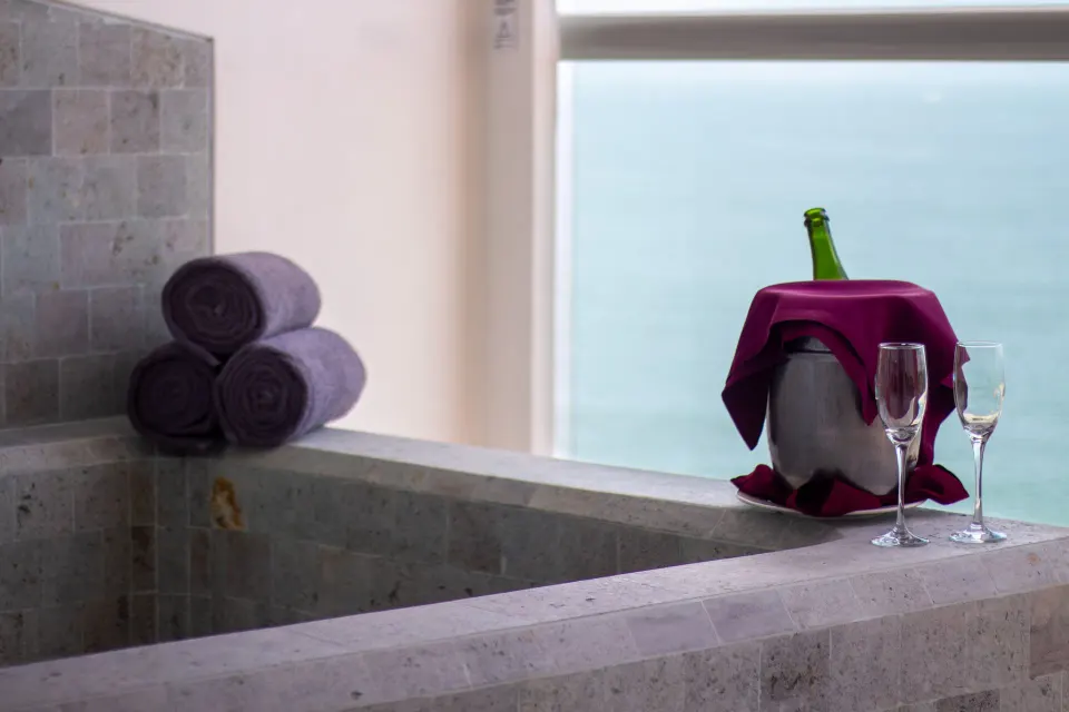 Stone soaking tub with towels and glasses in Deluxe Premium Ocean Front at Sunset Plaza Beach Resort & Spa Pto Vallarta.