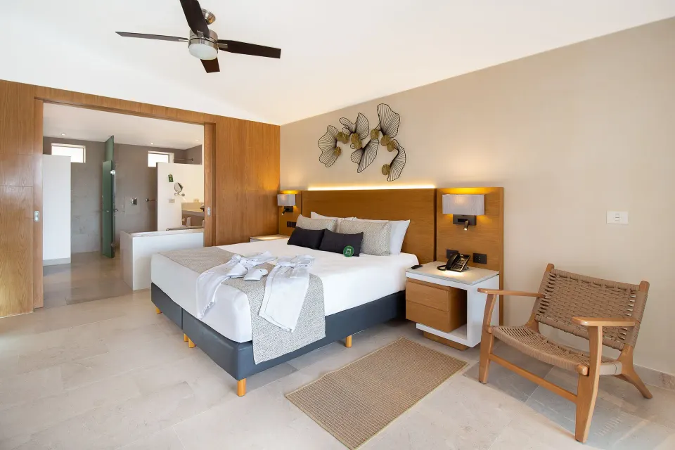 Suite Premium Ocean Front king bed with woven chair at Sunset Plaza Beach Resort & Spa Pto Vallarta.
