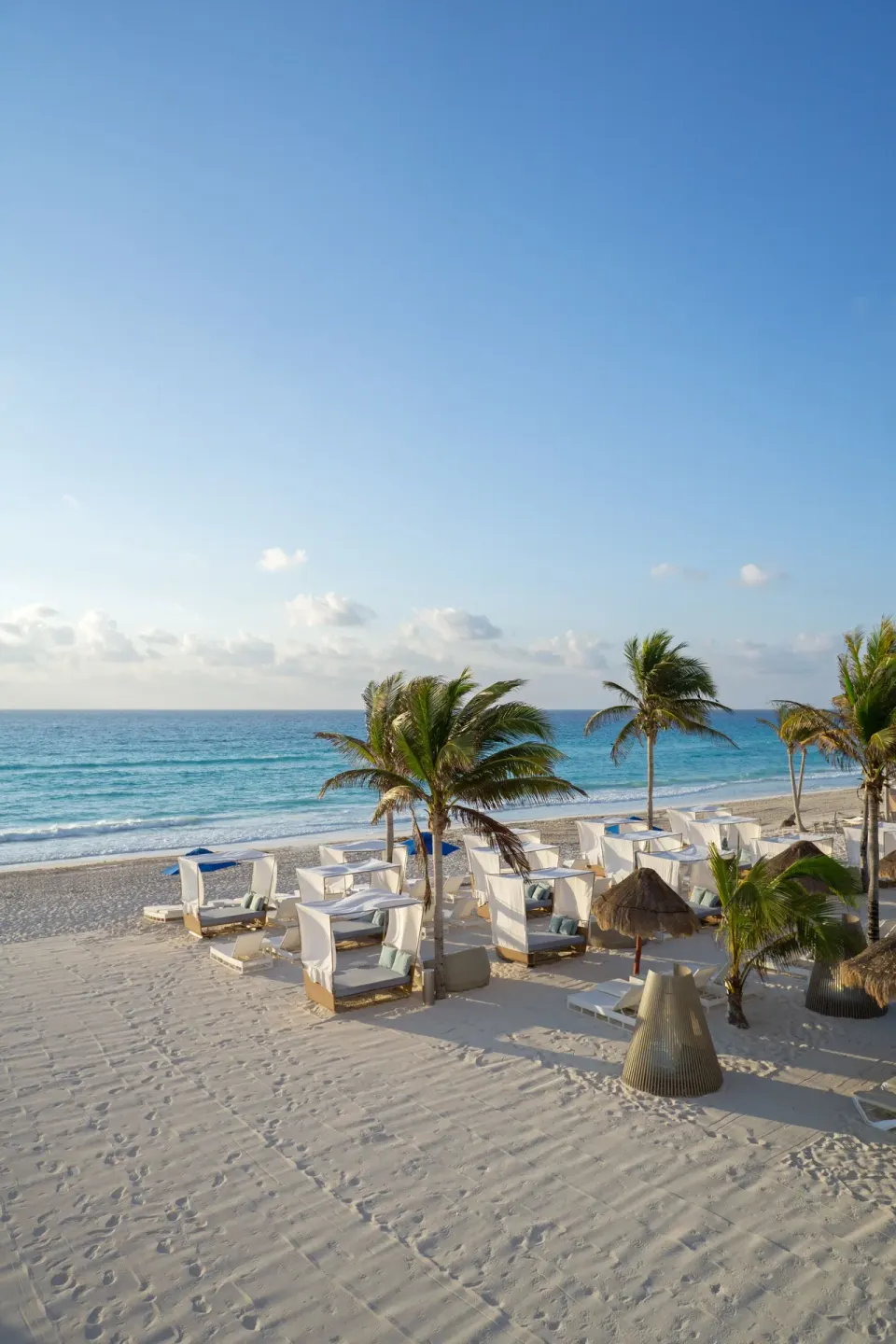 Beach cabanas, palm trees, white sand, and ocean at Sunset Royal Beach Resort.