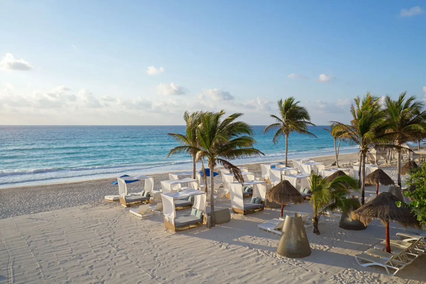 Beach cabanas, palms, and oceanfront sand at Sunset Royal Beach Resort.