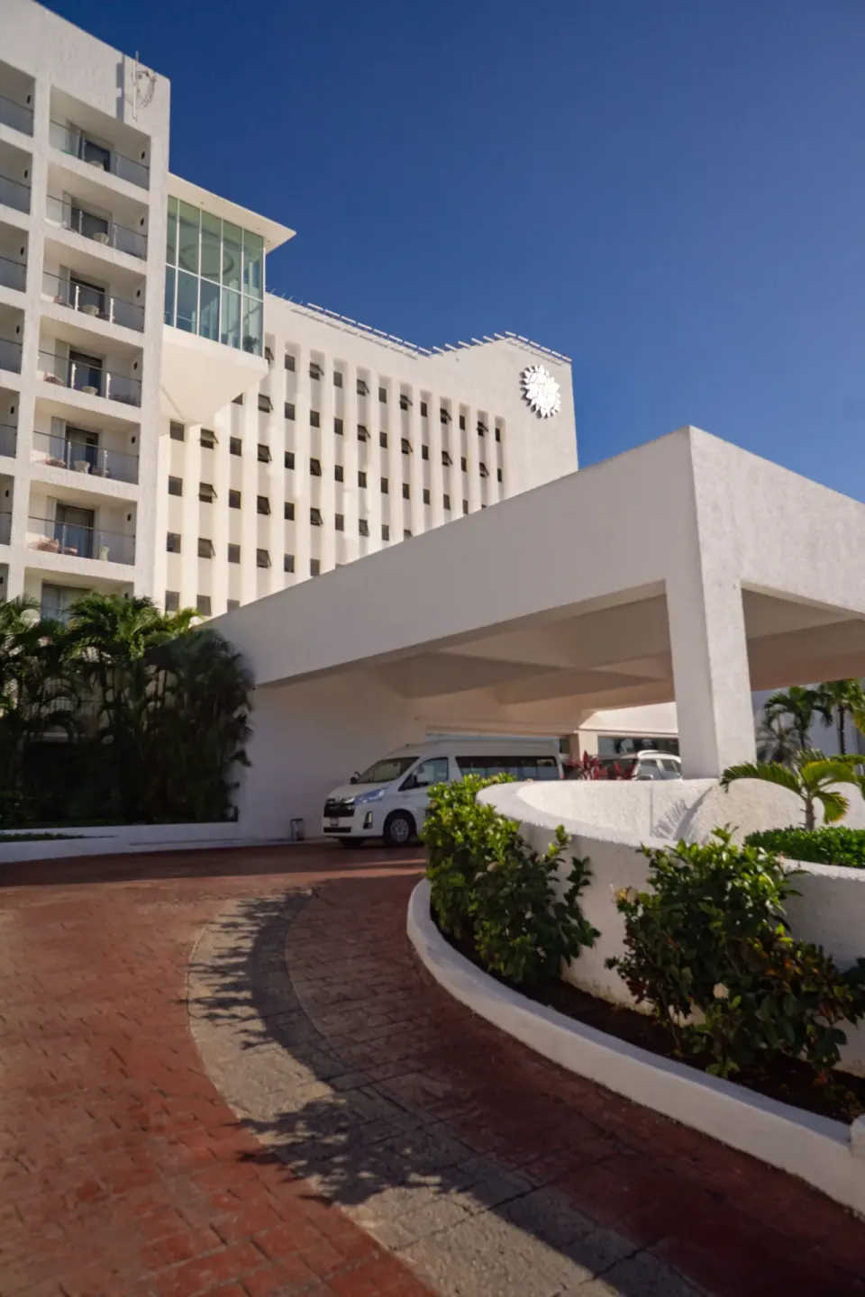 White hotel tower and covered entrance drive at Sunset Royal Beach Resort.