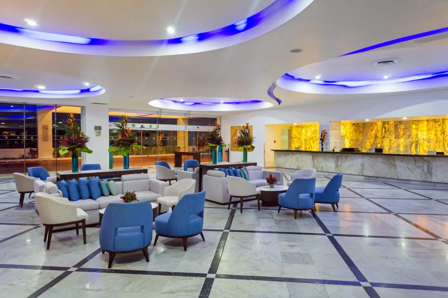 Lobby seating and reception desk with blue ceiling lights at Sunset Royal Beach Resort.