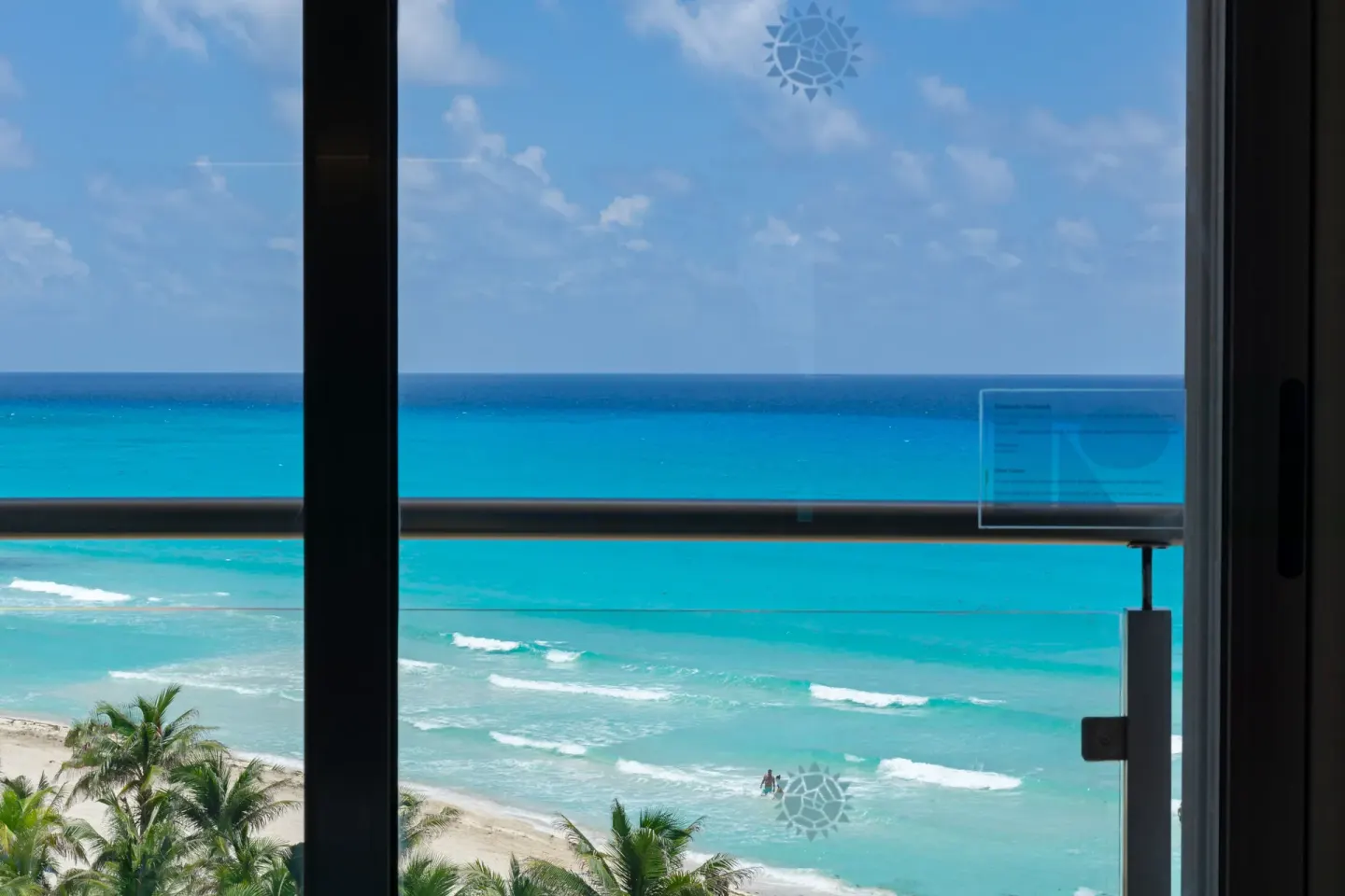 Ocean view through a glass balcony door at Sunset Royal Beach Resort.