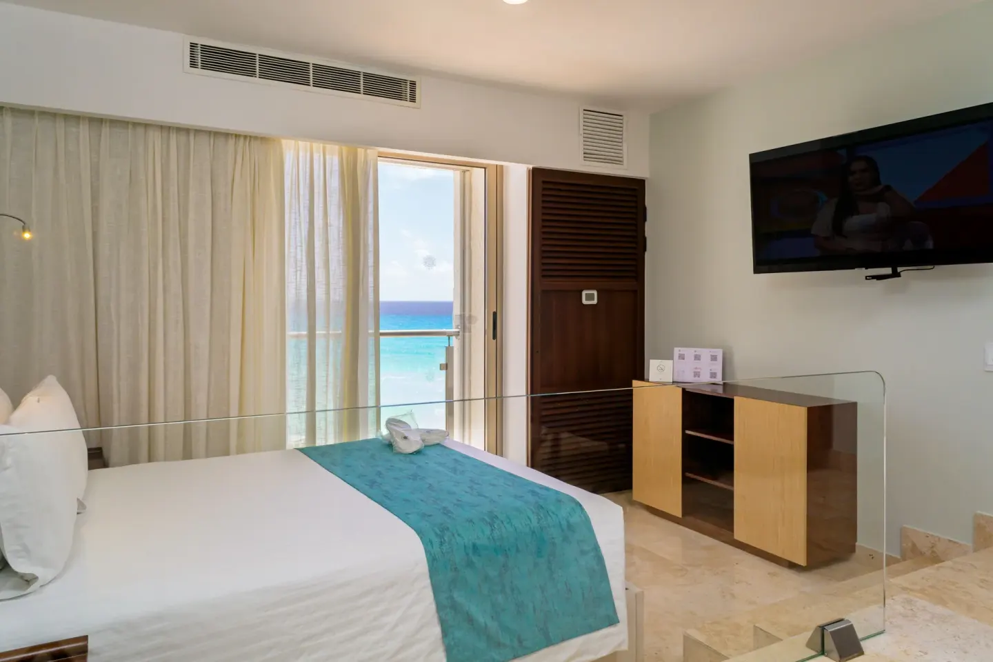 Ocean-view guest room with king bed and wall-mounted TV at Sunset Royal Beach Resort.