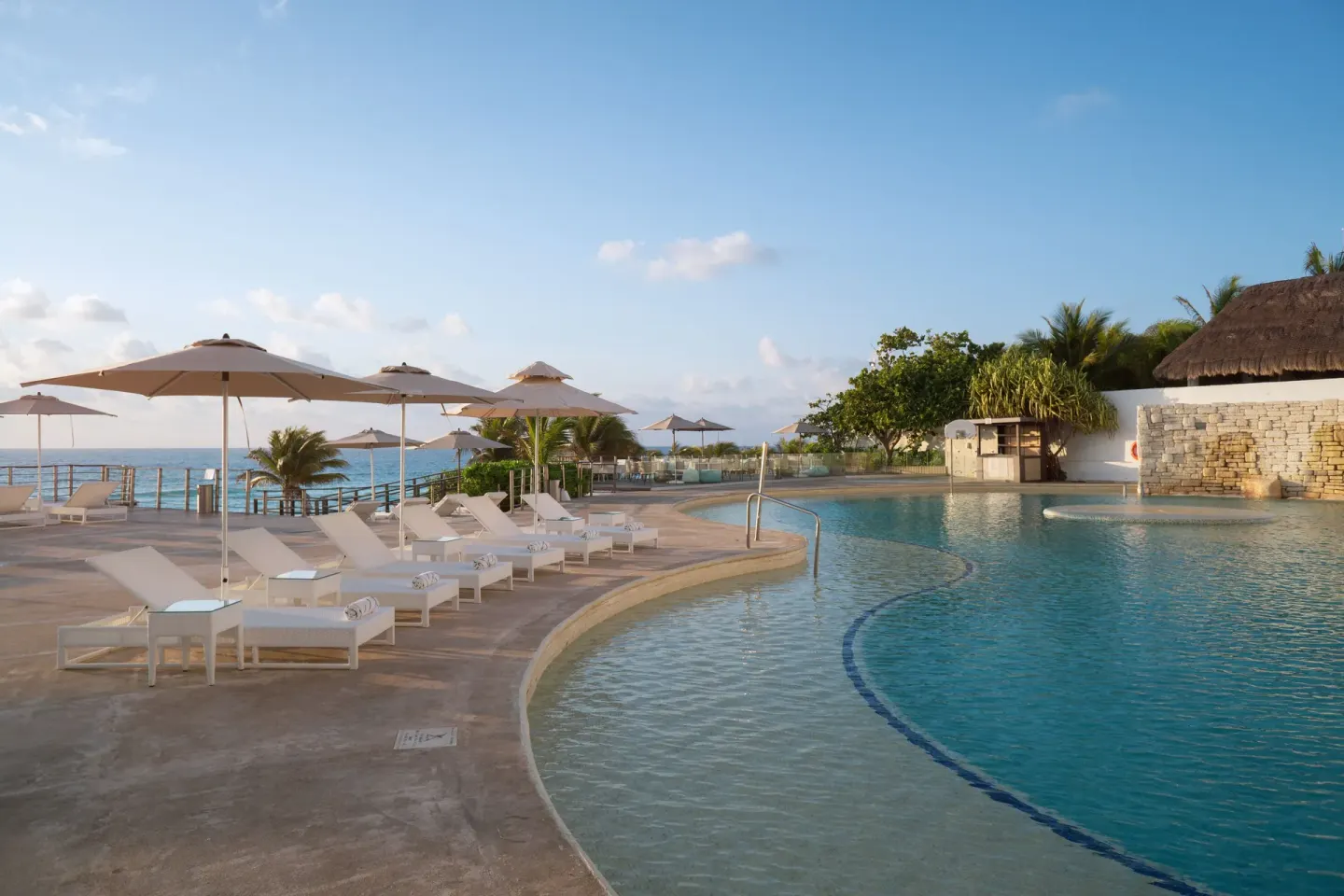 Oceanfront pool deck with loungers and umbrellas at Sunset Royal Beach Resort.