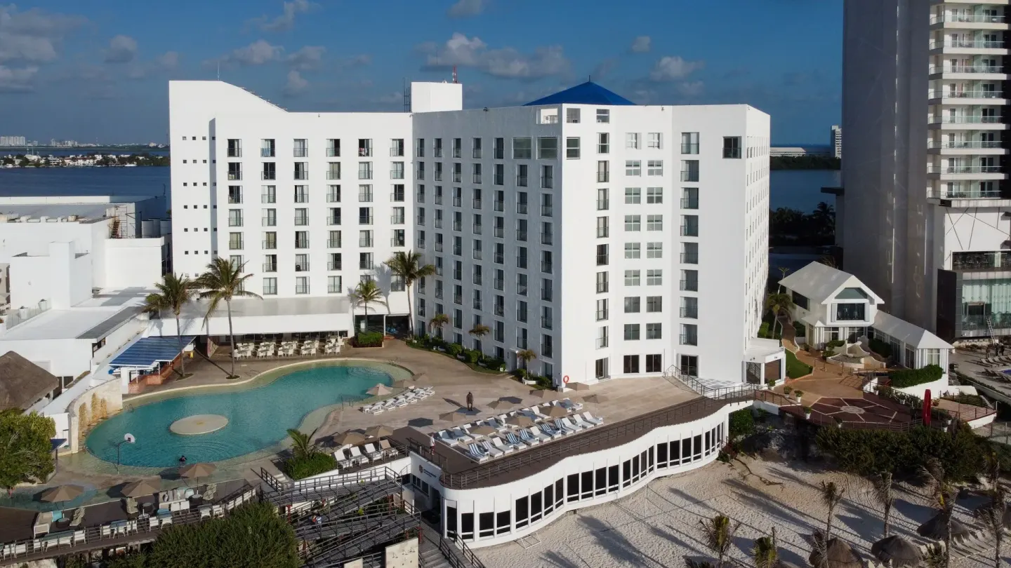 Pool deck, white guest-room building, and beach area at Sunset Royal Beach Resort.
