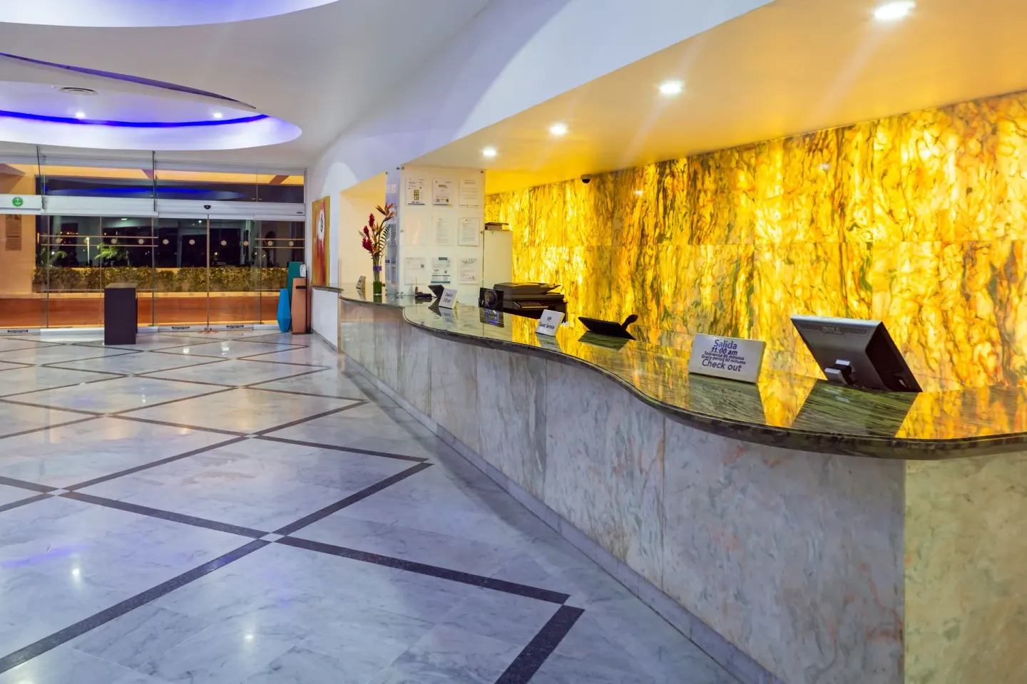 Reception desk with illuminated stone wall at Sunset Royal Beach Resort.