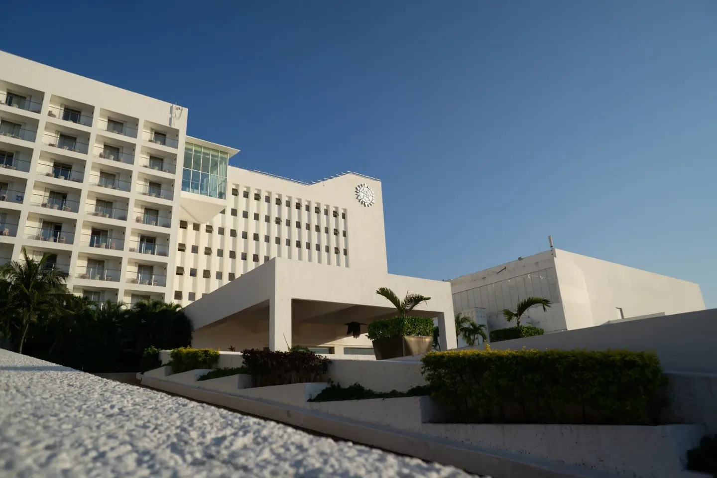 White resort buildings and landscaped entrance at Sunset Royal Beach Resort.