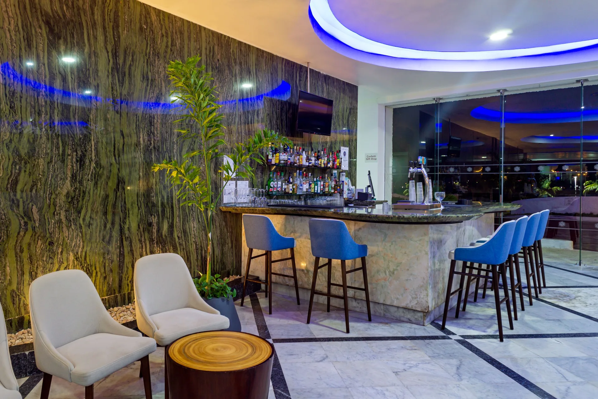 Lobby bar with blue stools and lounge seating at Sunset Royal Beach Resort.