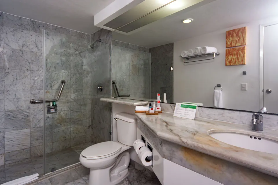 Family Room bathroom with marble vanity, toilet, and glass shower at Sunset Royal Beach Resort.