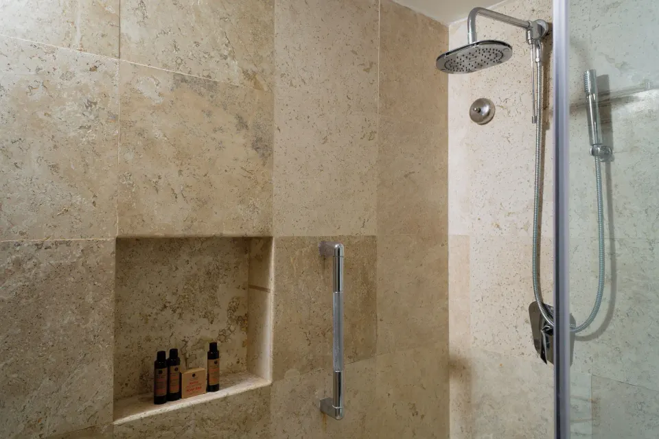 Standard Room bathroom shower with stone tile at Sunset Royal Beach Resort.