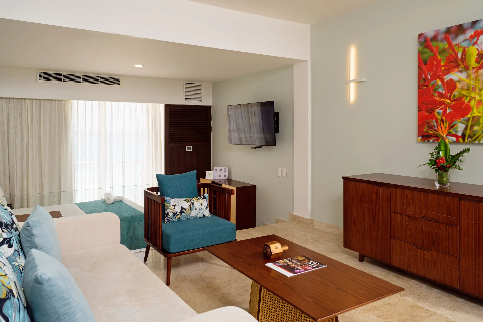 Standard Room living area with sofa, chair, TV and dresser at Sunset Royal Beach Resort.