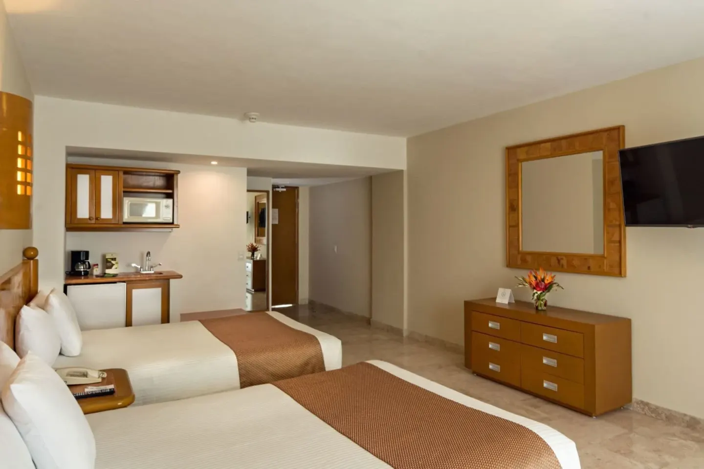 Studio room with two beds, kitchenette, dresser and TV at Sunset Royal Beach Resort.