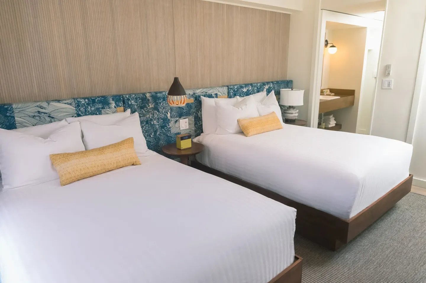 Guest room with two beds and a bathroom doorway at Surfjack Hotel & Swim Club.