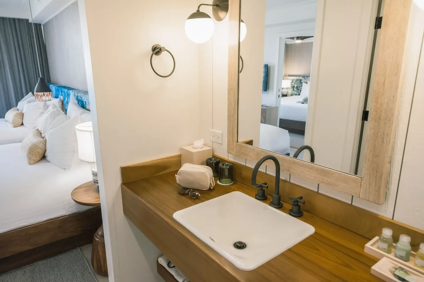 Guest room vanity with sink and mirror beside the bed at Surfjack Hotel & Swim Club.