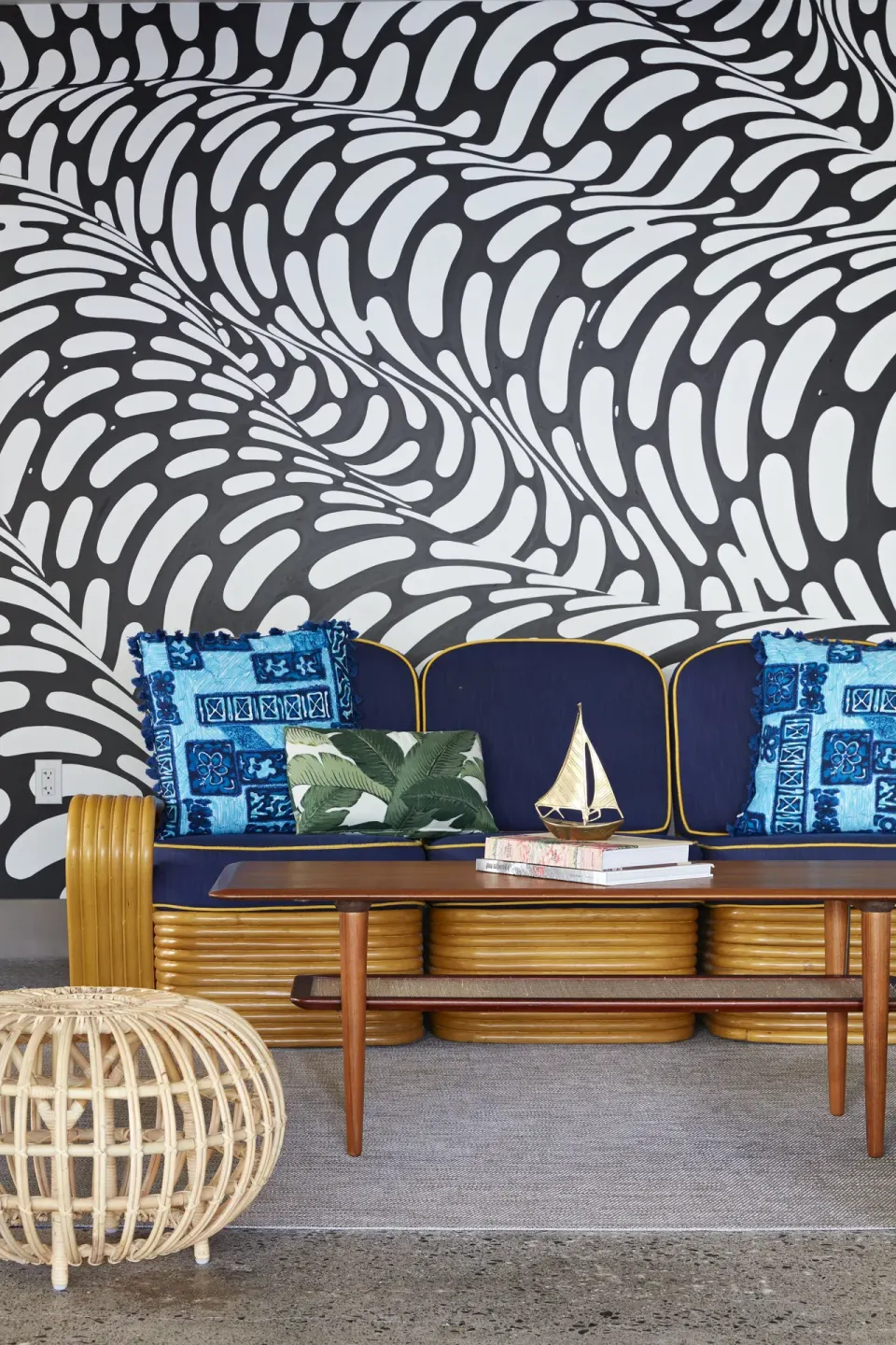 Blue rattan sofa and patterned wall mural in a lounge at Surfjack Hotel & Swim Club.