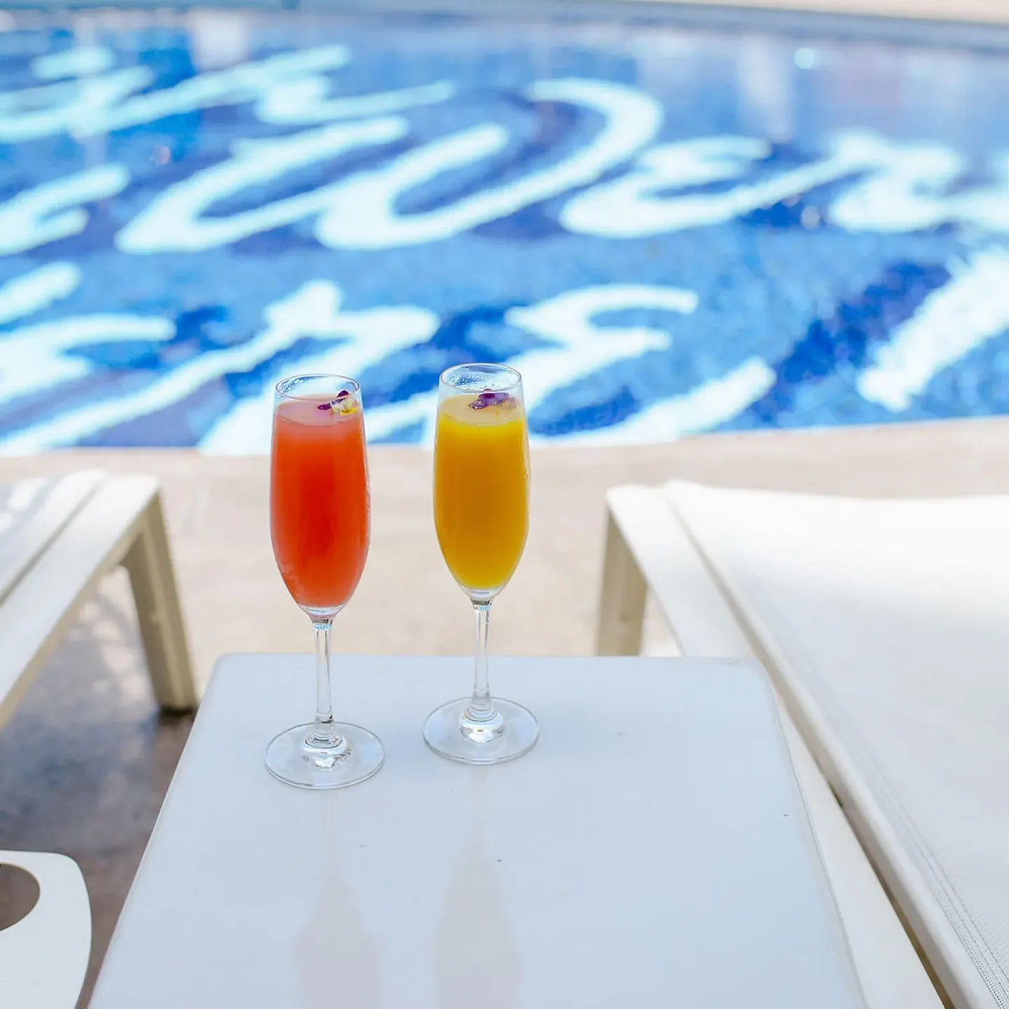 Two colorful drinks sit by the pool at Surfjack Hotel & Swim Club.
