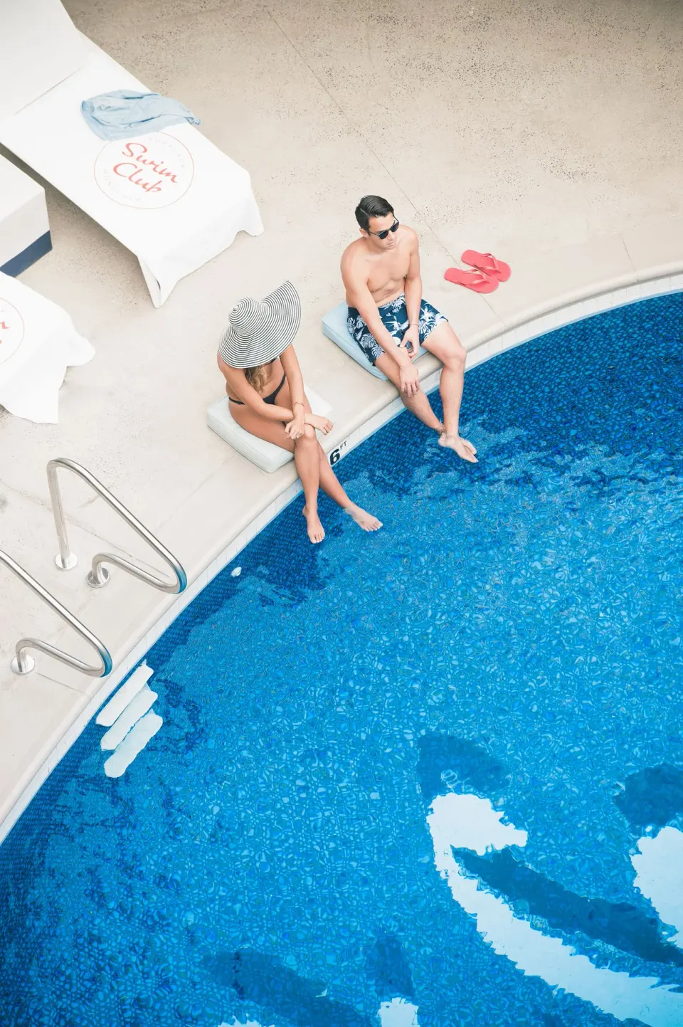 Two guests sit at the edge of the pool at Surfjack Hotel & Swim Club.