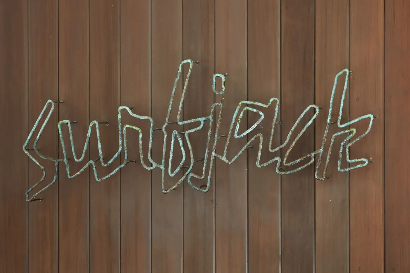 Surfjack script sign mounted on a wood wall at Surfjack Hotel & Swim Club.
