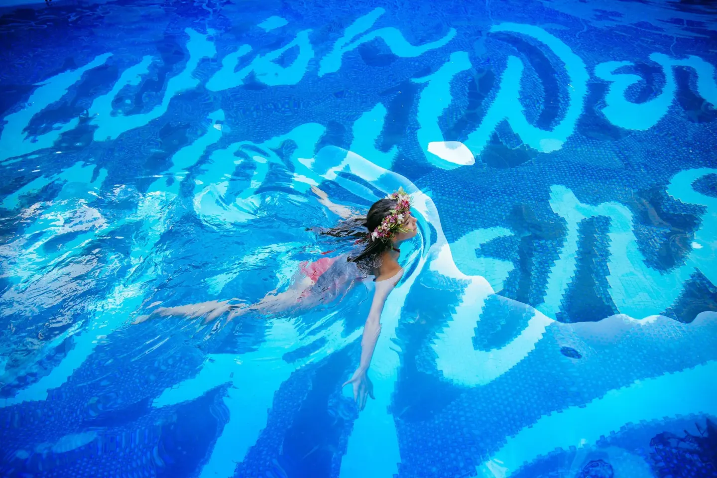 A swimmer floats across the blue pool at Surfjack Hotel & Swim Club.