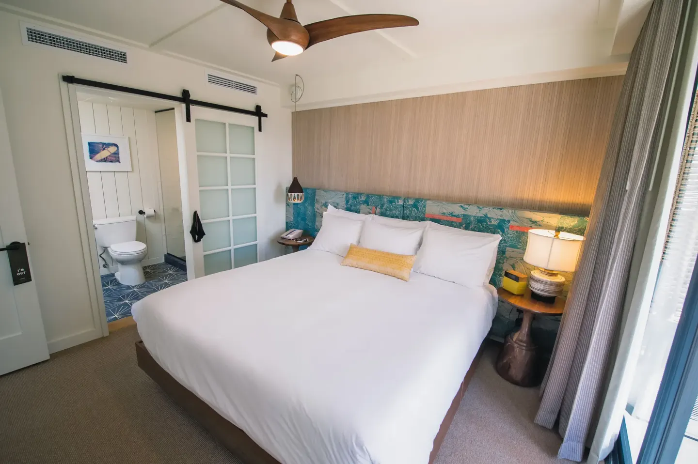 One Bedroom Suite king bed with sliding bathroom door at Surfjack Hotel & Swim Club.