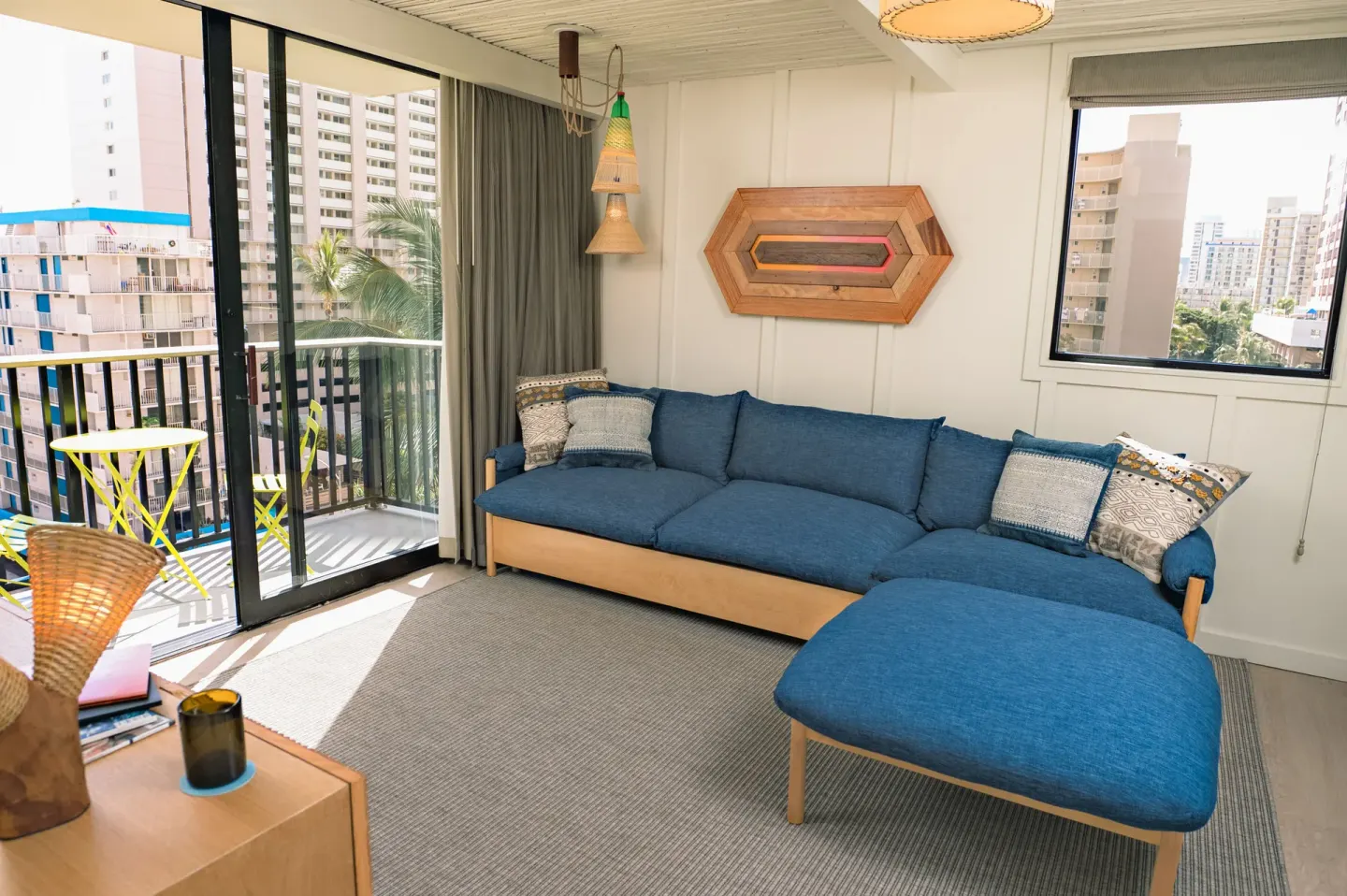One Bedroom Suite living area with blue sectional and balcony at Surfjack Hotel & Swim Club.