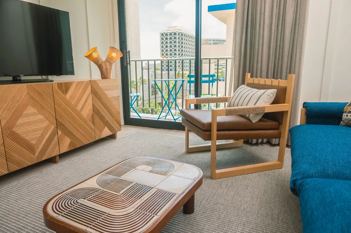 One Bedroom Suite lounge with TV, armchair, and balcony at Surfjack Hotel & Swim Club.