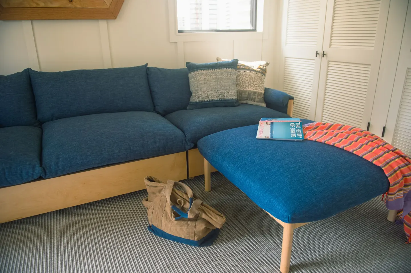 One Bedroom Suite blue sofa and ottoman with travel items at Surfjack Hotel & Swim Club.