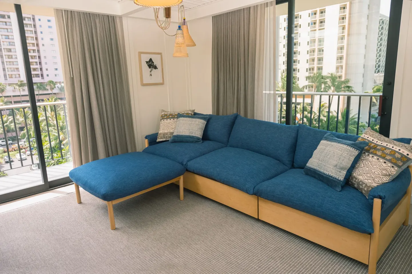 Corner living room with blue sectional and balcony doors at Surfjack Hotel & Swim Club.