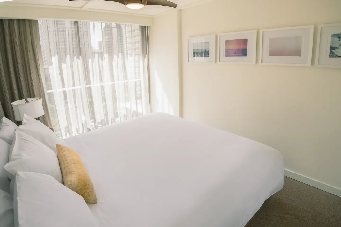Bedroom with a white bed, city-facing window, and framed art at Surfjack Hotel & Swim Club.