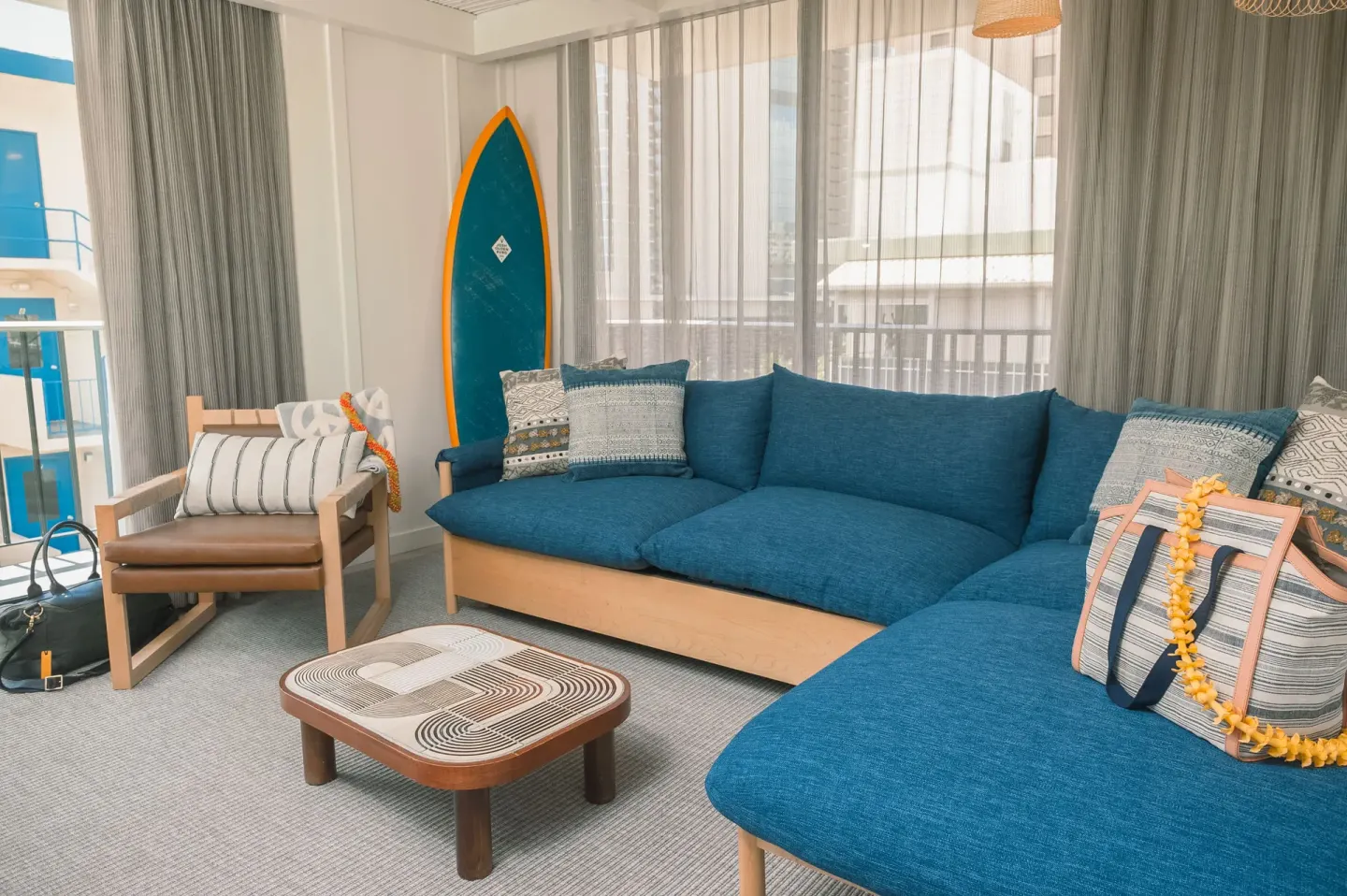 Living area with blue sectional sofa and surfboard decor at Surfjack Hotel & Swim Club.