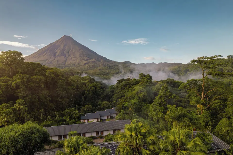 Arenal Volcano rising above lush rainforest and resort rooftops at Tabacón Thermal Resort & Spa