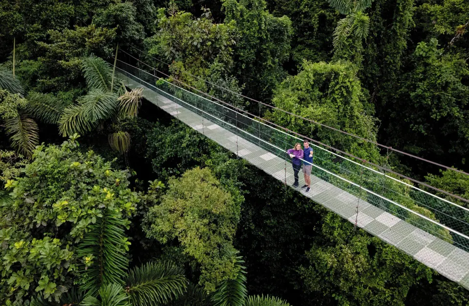 Couple standing on a suspended rainforest canopy bridge at Tabacón Thermal Resort & Spa