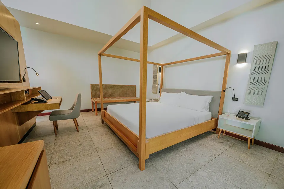 Bright guest room with canopy-style king bed and desk at Tabacón Thermal Resort & Spa