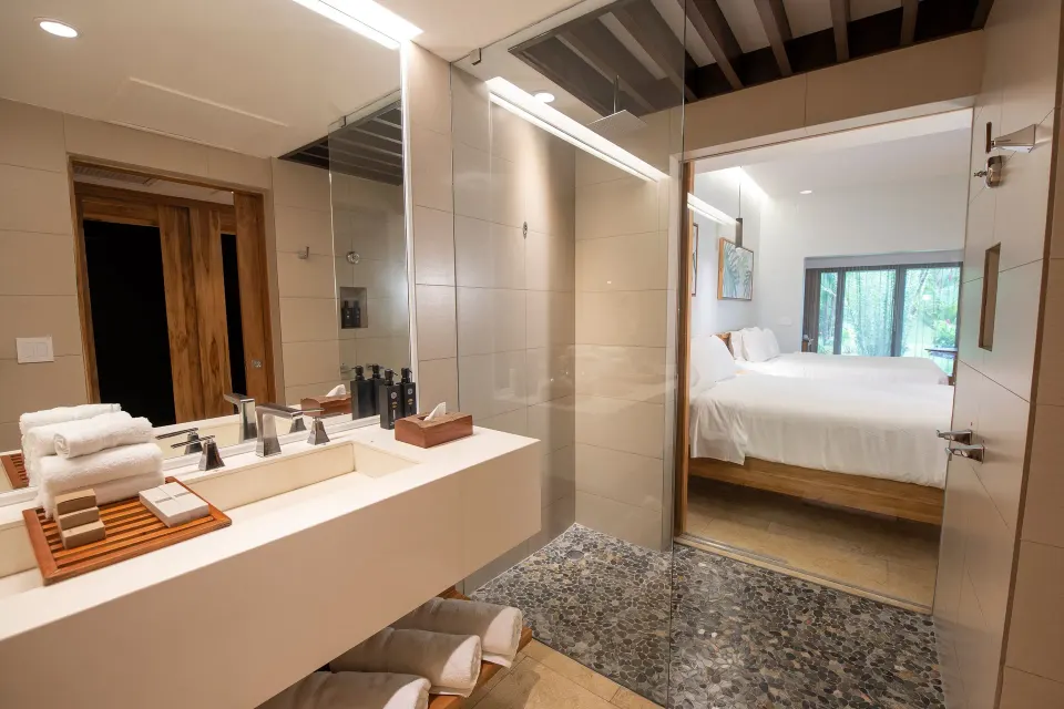 Bathroom sink and view into a bedroom with king bed at Tabacón Thermal Resort & Spa