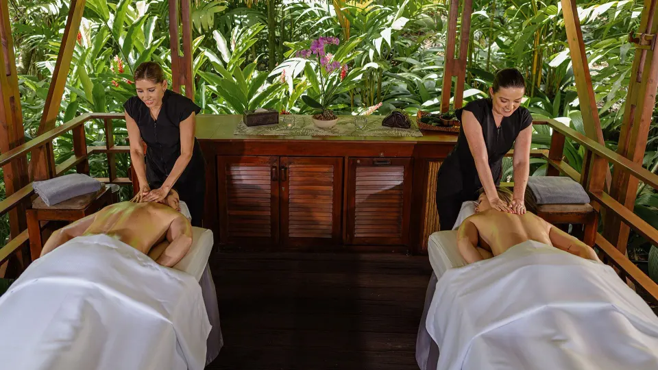 Two therapists giving outdoor massages on adjacent tables surrounded by jungle at Tabacón Thermal Resort & Spa