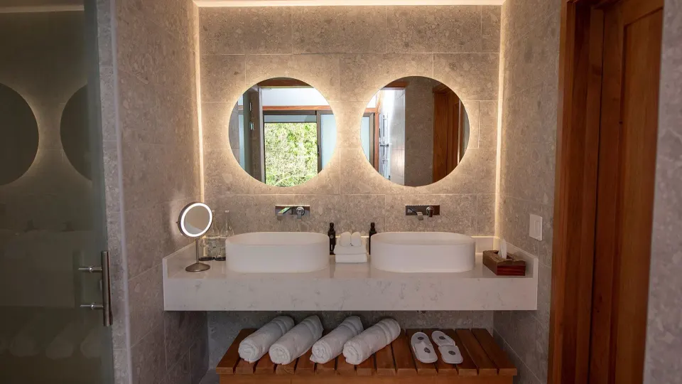 Double vanity bathroom with round backlit mirrors at Tabacón Thermal Resort & Spa