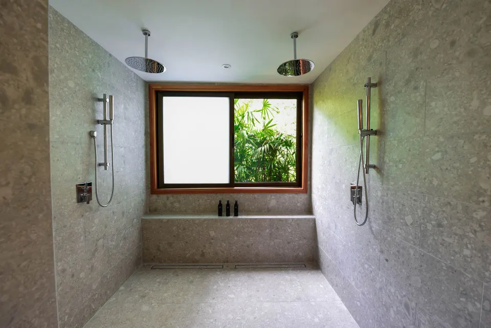 Dual rain showers and window with tropical view in a tiled bathroom at Tabacón Thermal Resort & Spa