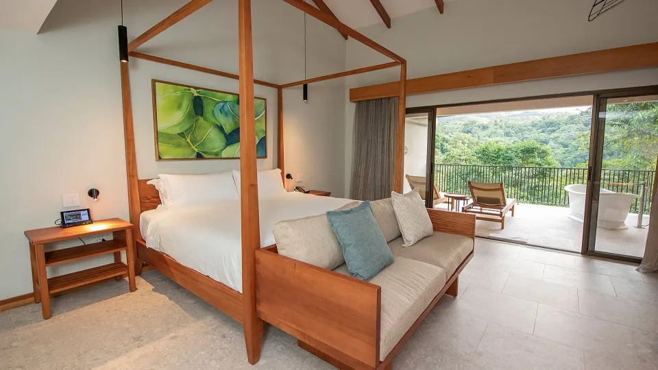 Four-poster bed opening to balcony and rainforest view at Tabacón Thermal Resort & Spa