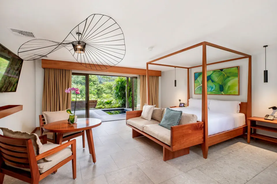 Four-poster king bed and seating area opening to a green terrace at Tabacón Thermal Resort & Spa.