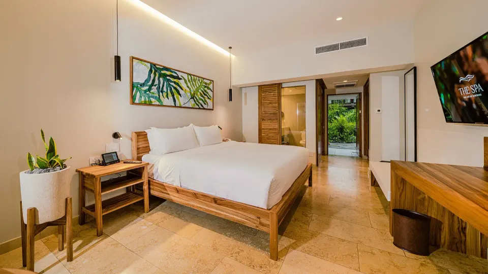 Warm-toned guest room with king bed and garden-facing doors at Tabacón Thermal Resort & Spa