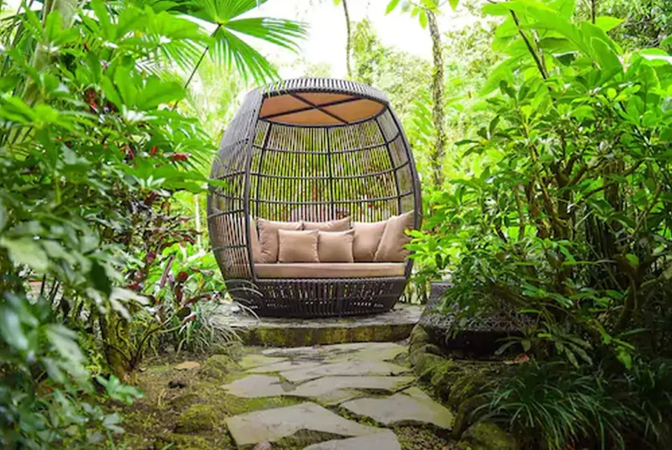 Wicker egg-shaped garden lounge seat tucked among tropical plants at Tabacón Thermal Resort & Spa