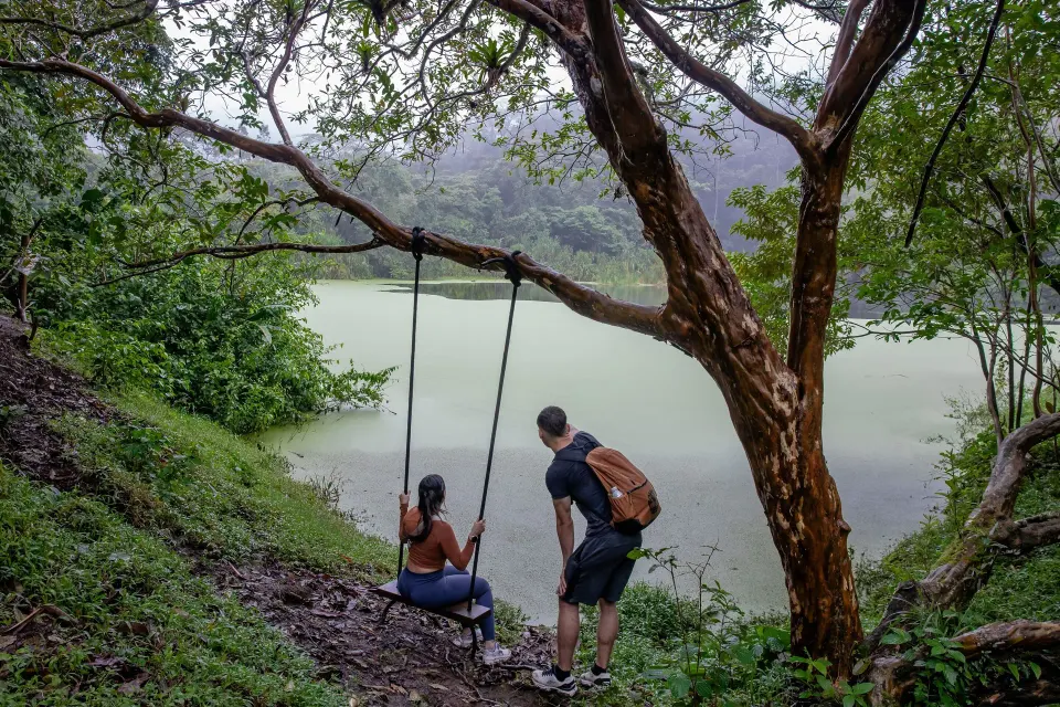 Two guests at a lakeside swing overlooking a misty lagoon at Tabacón Thermal Resort & Spa