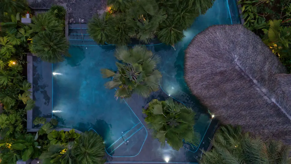 Night aerial shot of illuminated pool and thatched palapa at Tabacón Thermal Resort & Spa