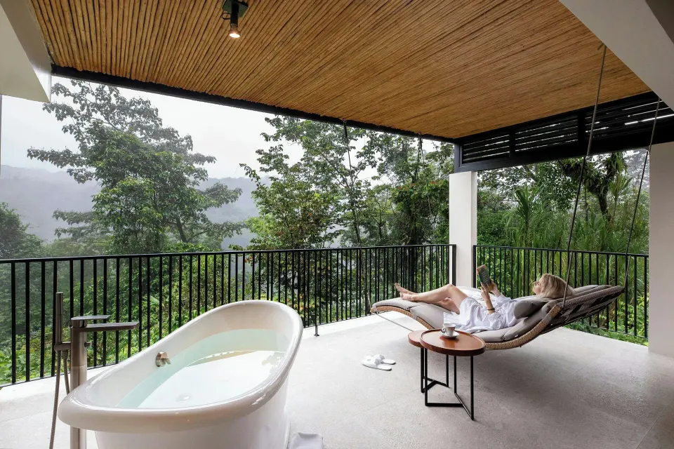 Outdoor terrace with freestanding bathtub and lounge chair overlooking the rainforest at Tabacón Thermal Resort & Spa.