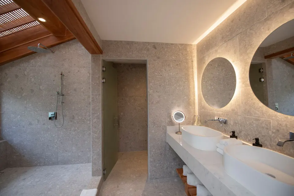Modern vanity with illuminated round mirrors in a suite bathroom at Tabacón Thermal Resort & Spa