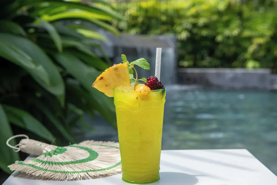 Yellow tropical cocktail garnished with fruit beside a pool at Tabacón Thermal Resort & Spa