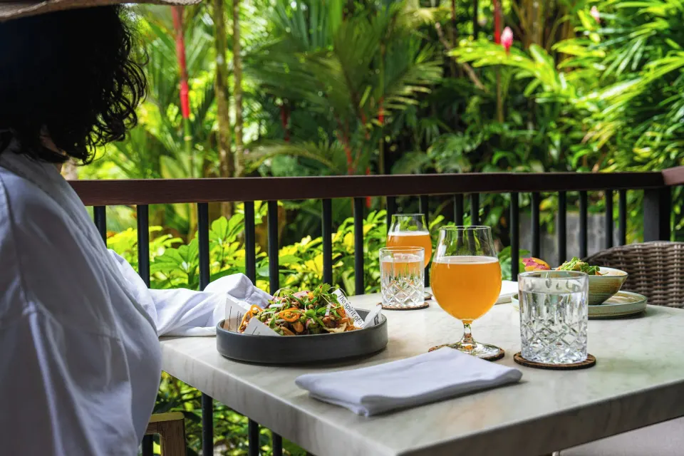 Table for one on a balcony with a salad and drinks overlooking lush tropical foliage at Tabacón Thermal Resort & Spa