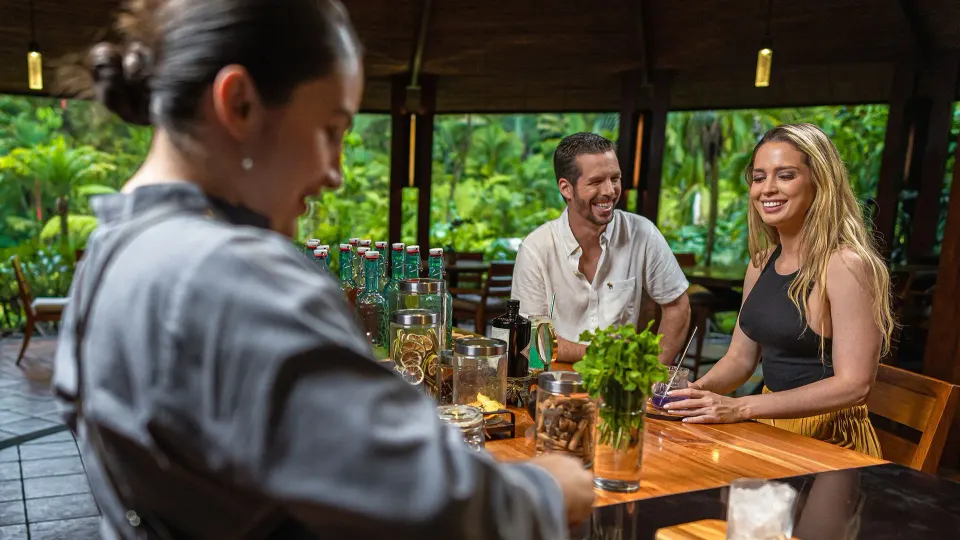 Bartender serving two guests at a wooden bar at Tabacón Thermal Resort & Spa